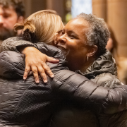 Two smiling parishioners share a hug during Sunday service at Trinity Church