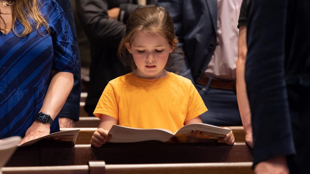 A child following along with the service using the worship bulletin at the 9:15am service