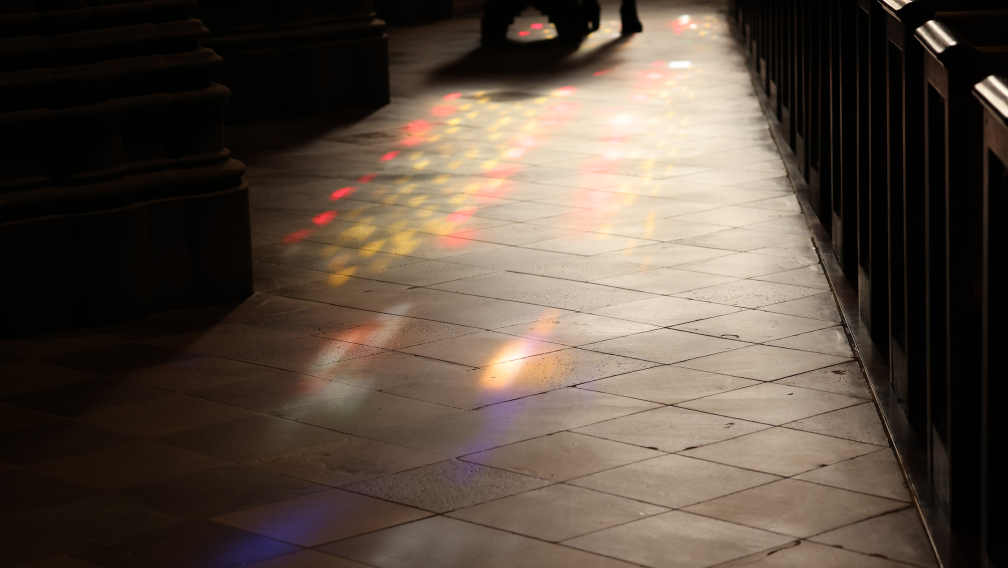 Colorful, stained-glass—filtered light shines on the stone floor of Trinity Church