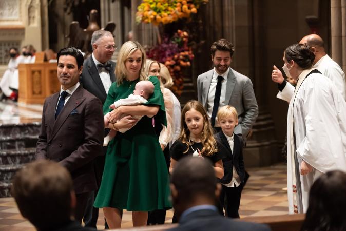 A mother carries her child after baptism in Trinity Church on All Saints Sunday 2021
