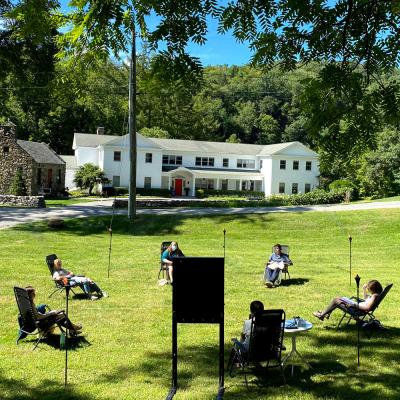 Socially-distanced group meets in a circle on the shaded green lawn of the Retreat Center