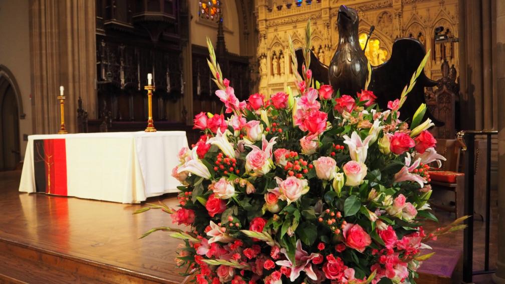 Bright pink flowers in front of the Trinity Church altar with the Lenten linen on it