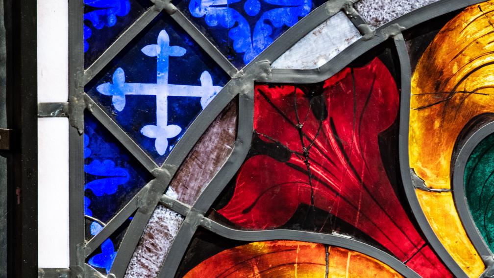 A close-up photo of brightly colored stained glass in Trinity Church, blue, red, warm yellow