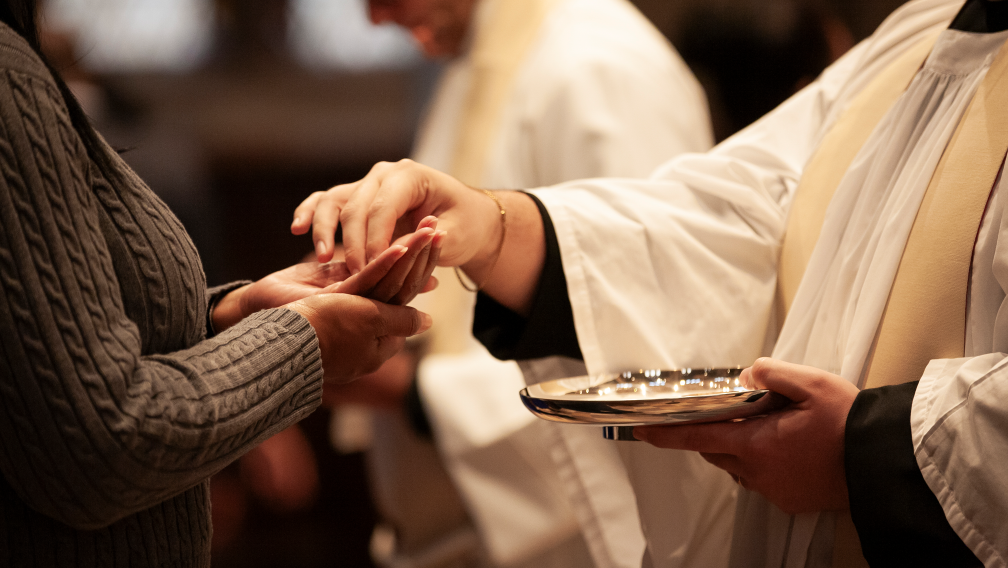 A close-up image of hands serving Communion in Trinity Church