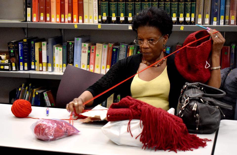 A member of Trinity Knitters makes a red scarf in the Parish Center.