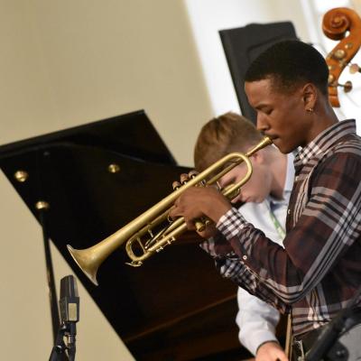 A teenage male African American saxophone player on the right side of the picture  