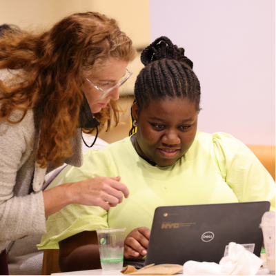 Jenn Chinn assists a young woman using a laptop.